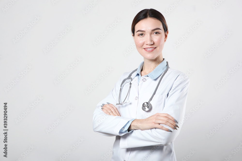Young woman doctor on light background with place to place text Young woman doctor on light background with place to place text