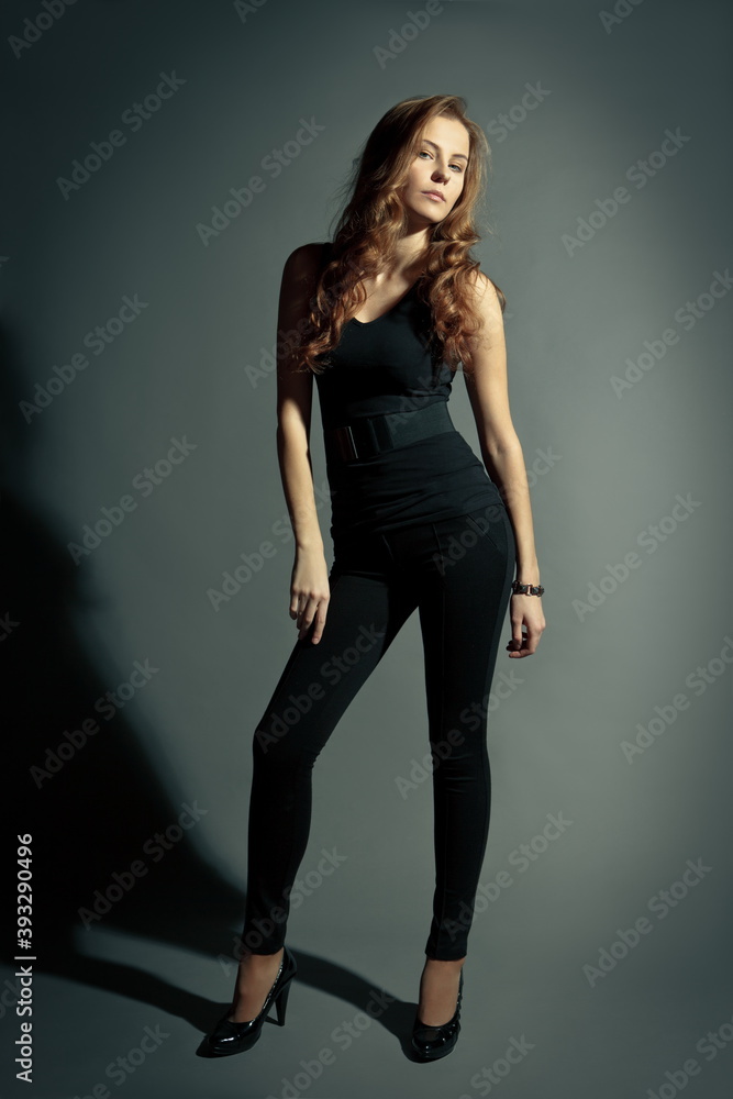 beautiful slender blonde girl in black tights and a tank top on a gray background beautiful slender blonde girl in black tights and a tank top on a gray background