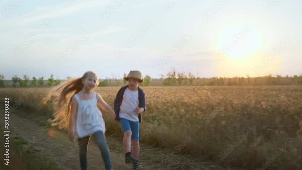 friendship in the countryside, happy girl and down syndrome boy jumping while walking holding hands in field on the background of sunset friendship in the countryside, happy girl and down syndrome boy jumping while walking holding hands in field on the background of sunset