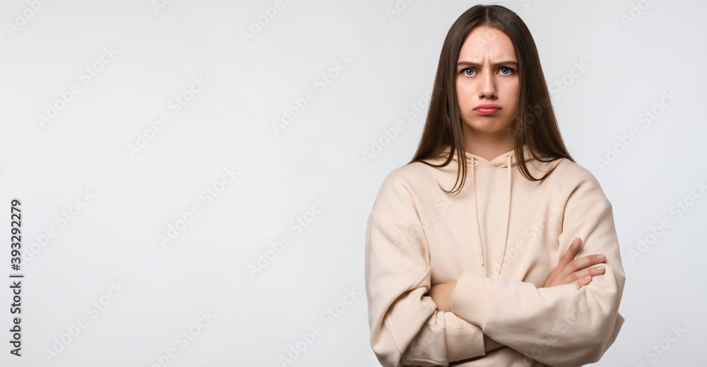 Photo of Offended girl holding hands crossed, looking at camera. Place for ad Photo of Offended girl holding hands crossed, looking at camera. Place for ad