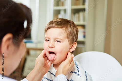 Doctor palpates tonsils on child with sore throat