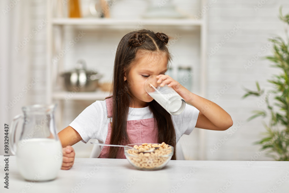 cute little girl eating breakfast: cereal with the milk. child drinking milk in the kitchen. healthy breakfast cute little girl eating breakfast: cereal with the milk. child drinking milk in the kitchen. healthy breakfast