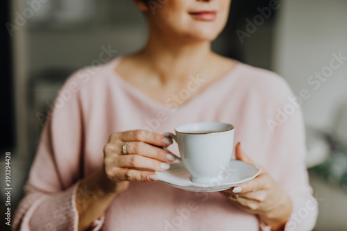 Happy woman enjoying a warm cup of tea for breakfast