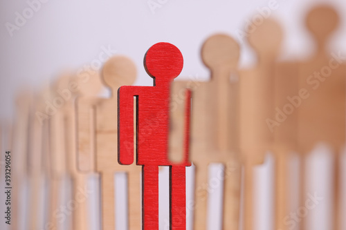 Bild auf Leinwand Among group of wooden toy men there is one red in line closeup
