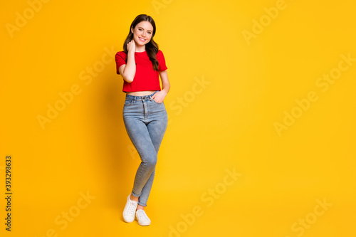 Full length photo of charming lady good mood wear red t-shirt cropped top jeans footwear isolated yellow color background