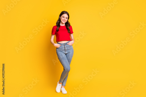 Full size photo of attractive lady standing arms pockets wear casual red cropped top jeans isolated yellow color background