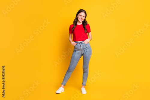 Full size photo of lady good mood arms pockets wear casual red cropped top jeans footwear isolated yellow color background