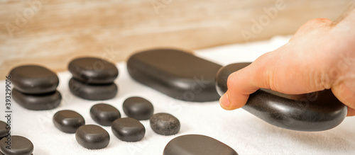 Canvas Print Hand of masseur lays out massage stones on the table in spa salon