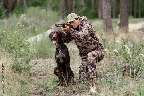 Man Aiming with Rifle Gun Dog Sitting Quietly.