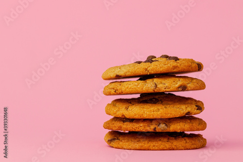 Stacked chocolate chip cookies against pink background