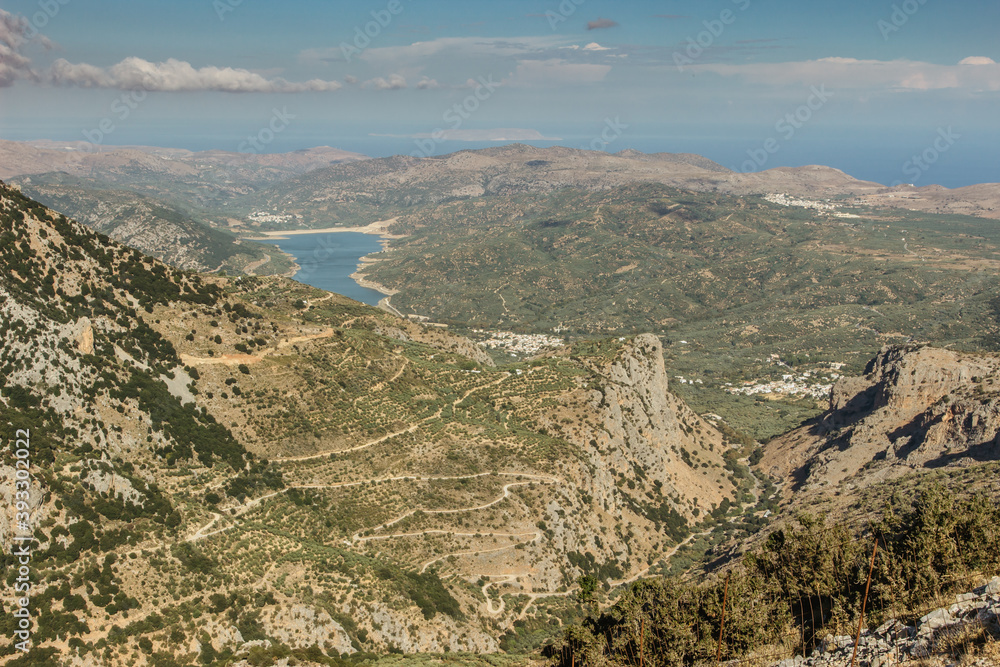 Aerial view of summer landscape in Crete,Greece.Popular travel destination.Amazing scenery of Greek nature.Mountain road serpentine through Lasithi Plateau.Top view of sea and mountains.Summer holiday