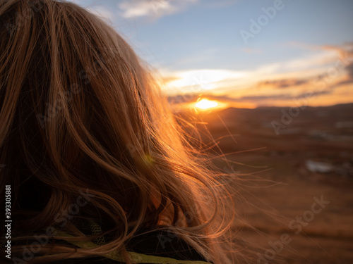 VIEW FROM BEHIND THE HEAD OF A BLOND WOMAN LOOKING AT SUNSET ON A HILL IN CONSUEGRA, SPAIN © RODRIGO