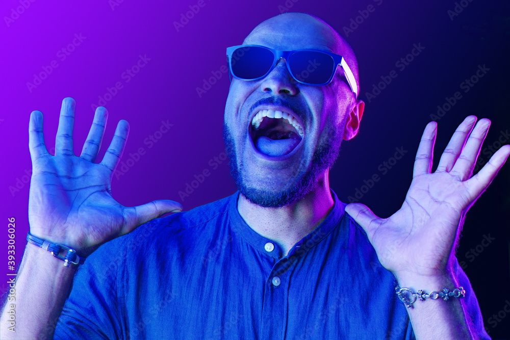 Black man in glasses shouting with happiness in neon light Black man in glasses shouting with happiness in neon light
