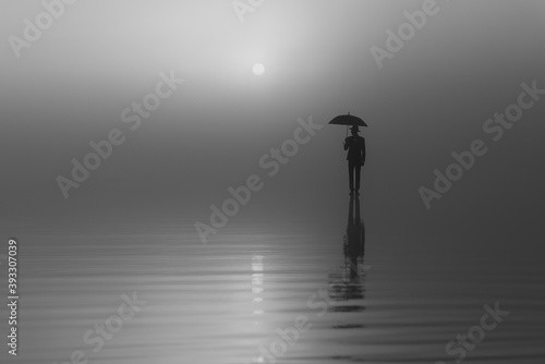surreal silhouette of a man in a suit and hat with an umbrella standing on the water