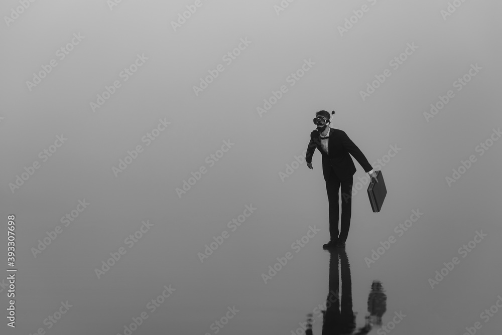 surreal portrait of a man in a suit and mask with a diving tube with a briefcase in his hands standing on the water surreal portrait of a man in a suit and mask with a diving tube with a briefcase in his hands standing on the water
