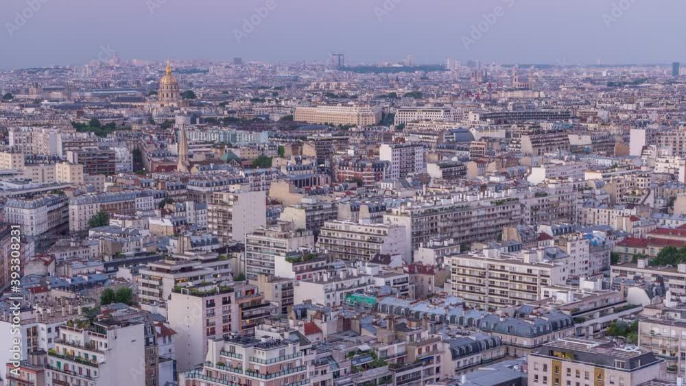Aerial panorama above houses rooftops in a Paris day to night transition timelapse. Evening view with les invalides and other sightseeings illuminated after sunset Aerial panorama above houses rooftops in a Paris day to night transition timelapse. Evening view with les invalides and other sightseeings illuminated after sunset