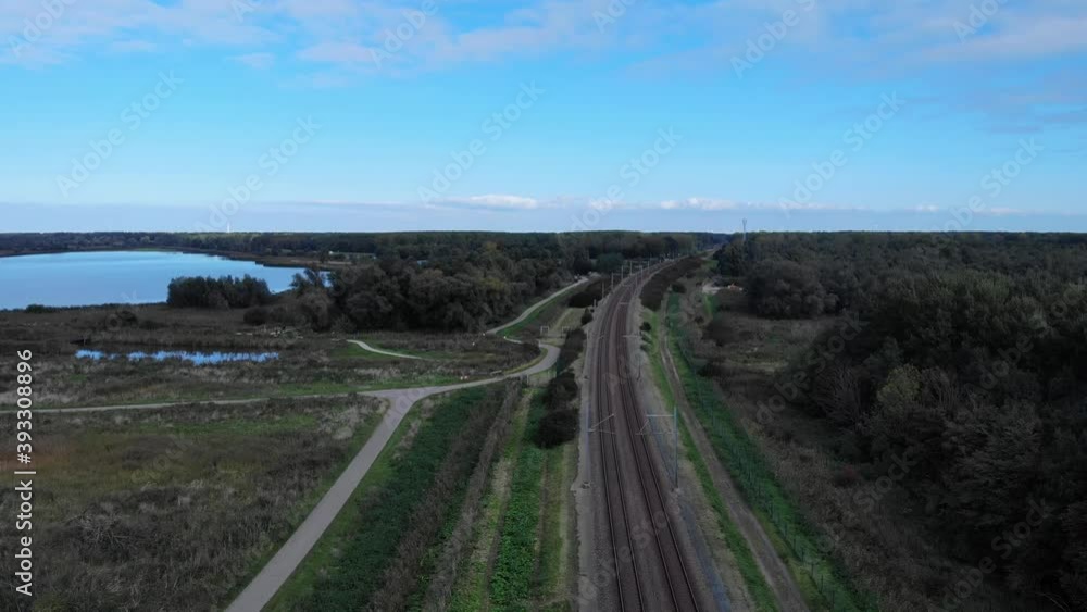Dutch railway track through the nature till the horizon while the drone is going down in a pedestal shot Dutch railway track through the nature till the horizon while the drone is going down in a pedestal shot