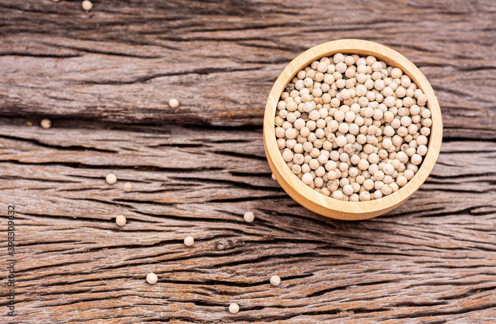 White peppercorns in a cup on a wooden table White peppercorns in a cup on a wooden table