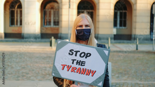 Obraz na płótnie Young woman in protective mask calling to stop the tyranny by holding steamer