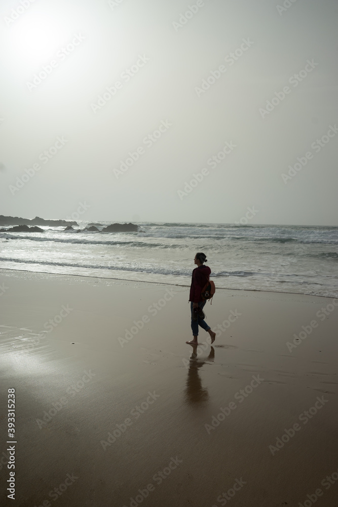 Naklejka premium Woman walking on the beach, foggy day