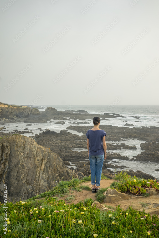 Back view of a woman looking the see, loneliness concept in winter season grey foggy day