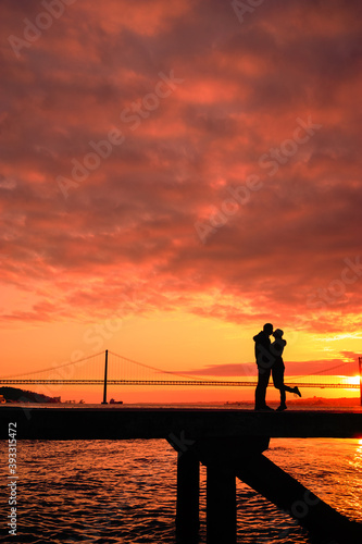 Silhouette of lovers kissing with a bridge in the background sunset time Lisbon