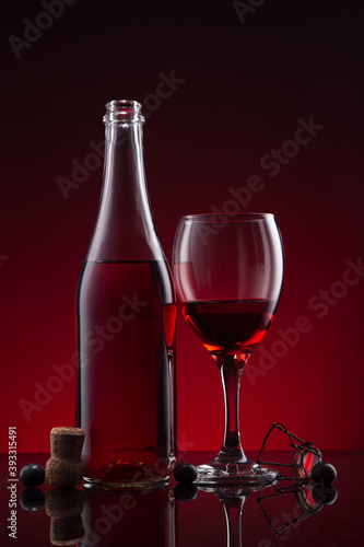 Bottle and glass of Lambrusco wine on red dark background.