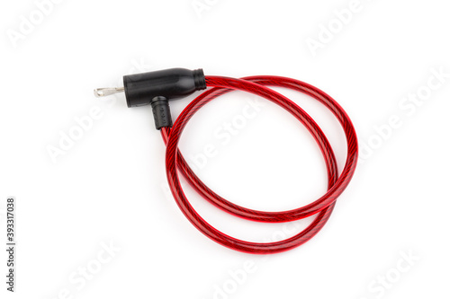 Flexible red bicycle cable with key on white background. Security and safety concept.