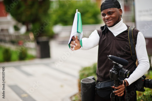 Young professional african american videographer holding professional camera with nigerian flags in hands. photo