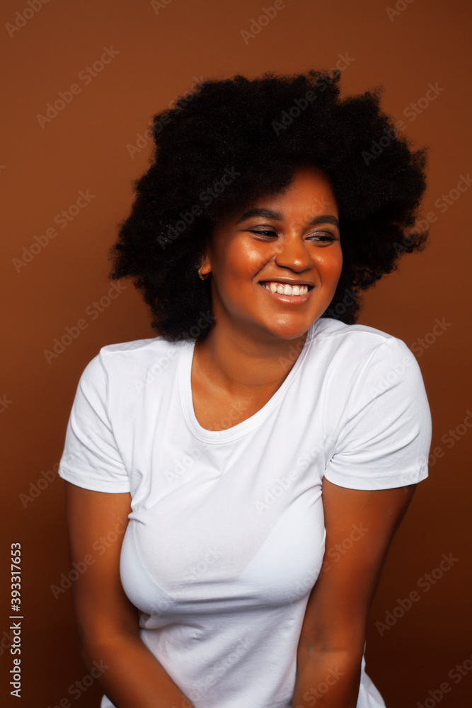 pretty young african american woman with curly hair posing cheerful gesturing on brown background, lifestyle people concept