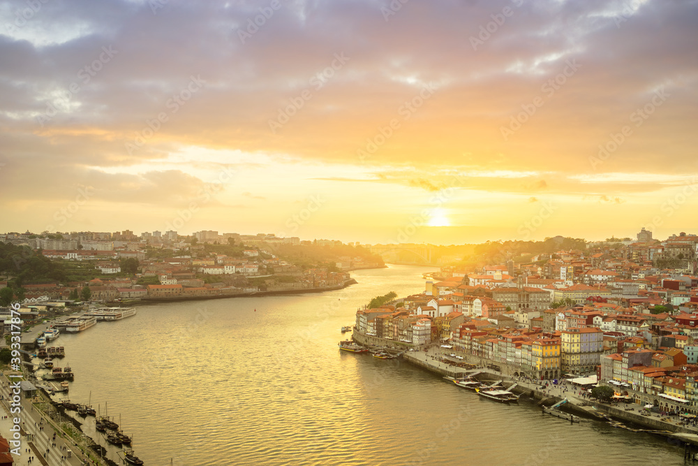 Porto, Portugal old town ribeira aerial promenade view with colorful houses, Douro river and boats at sunset