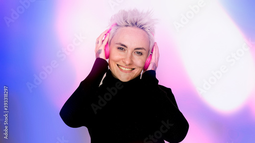 Happy woman listening to music on her pink headphones