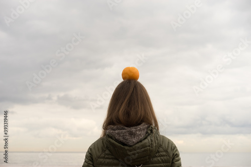 woman with orange on her head with ocean background
