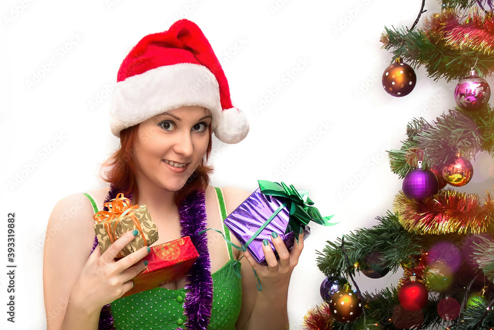 Young woman in Santa hat receives gifts near  Christmas tree on white background.