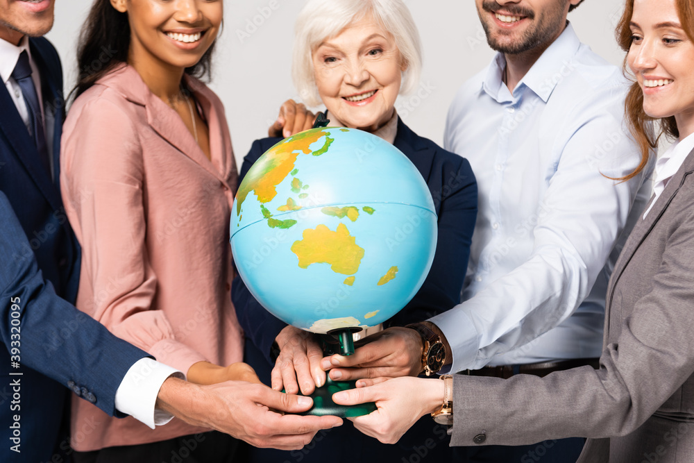 Globe in hands of smiling multiethnic businesspeople on blurred background isolated on grey Globe in hands of smiling multiethnic businesspeople on blurred background isolated on grey
