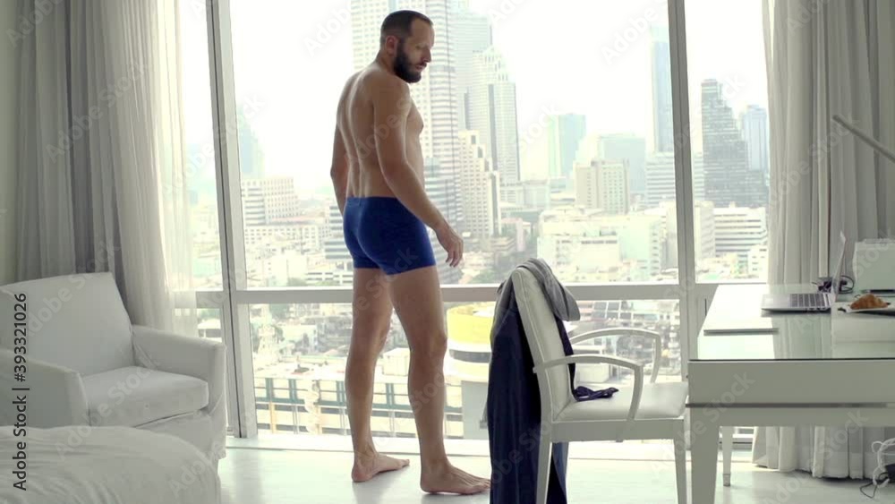 Young businessman dressing up shirt and looking through the window, super slow motion
Young businessman dressing up shirt and looking through the window, super slow motion