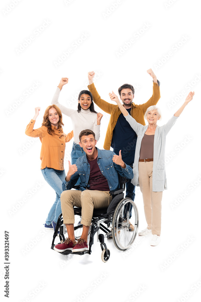Excited multiethnic friends showing like and yeah gestures near friend in wheelchair on white background Excited multiethnic friends showing like and yeah gestures near friend in wheelchair on white background