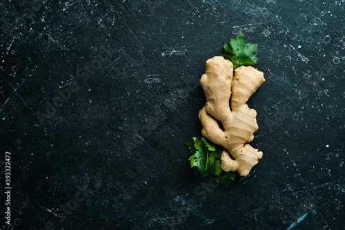 Fresh ginger root on a black stone background. Top view. Rustic style.