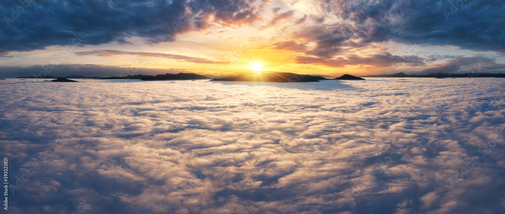 Beautiful sunset sky above the clouds with silhouettes of mountain peaks with dramatic light.