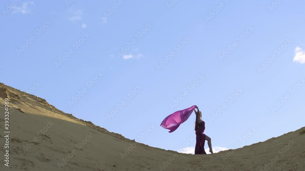 Young beautiful woman dancing Middle Eastern dance on sand at sunset. Extreme long shot. Young beautiful woman dancing Middle Eastern dance on sand at sunset. Extreme long shot.