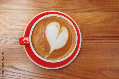 Red cup of coffee with heart shaped latte art