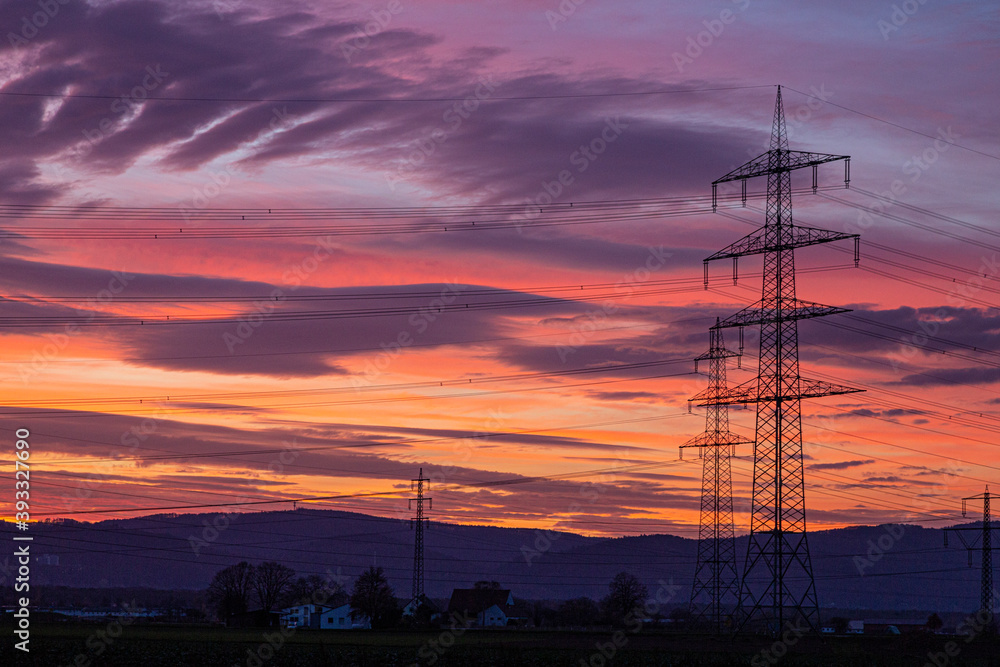Image of a colorful and high-contrast sunrise with bright cloud formations and contours of power poles