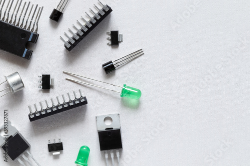 Electronic components over white background with copy space. There are microcontrollers, transistors, green LEDs, microcircuits, thyristors.