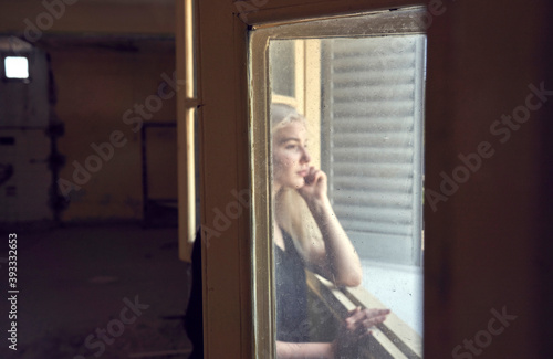 Close up portrait of beautiful blond young woman looking through hotel window