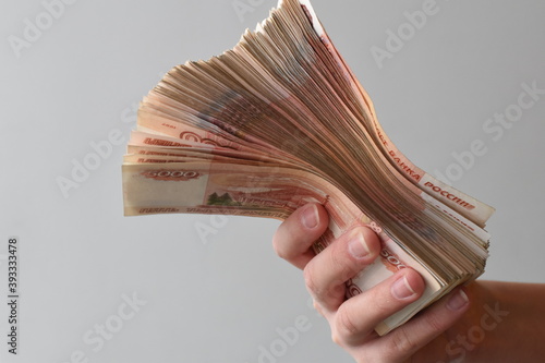 The hand holds out a bundle of five thousand Russian bills. Copy space