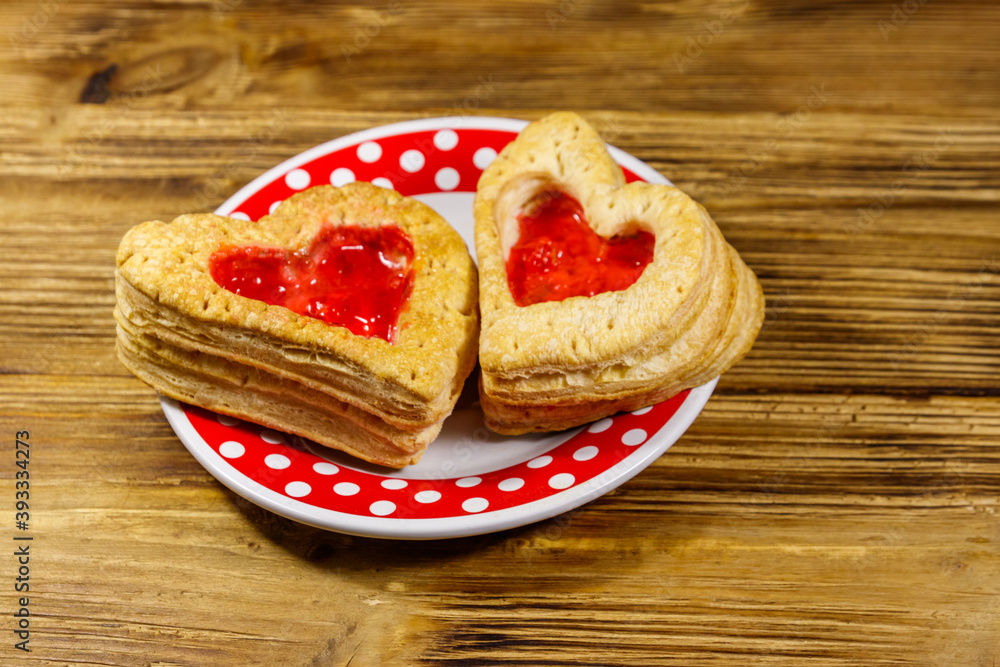 Heart shaped puff cookies with jam on a wooden table. Dessert on Valentine`s Day