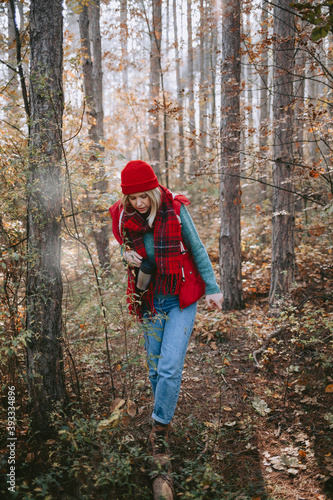 Woman backpacker walking through a forest with a thermos in her hand © Suteren Studio