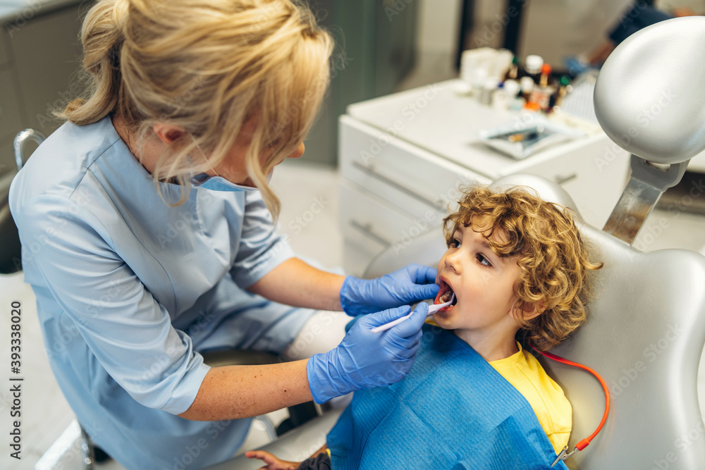Cute young boy visiting dentist, having his teeth checked by female dentist in dental office. Cute young boy visiting dentist, having his teeth checked by female dentist in dental office.