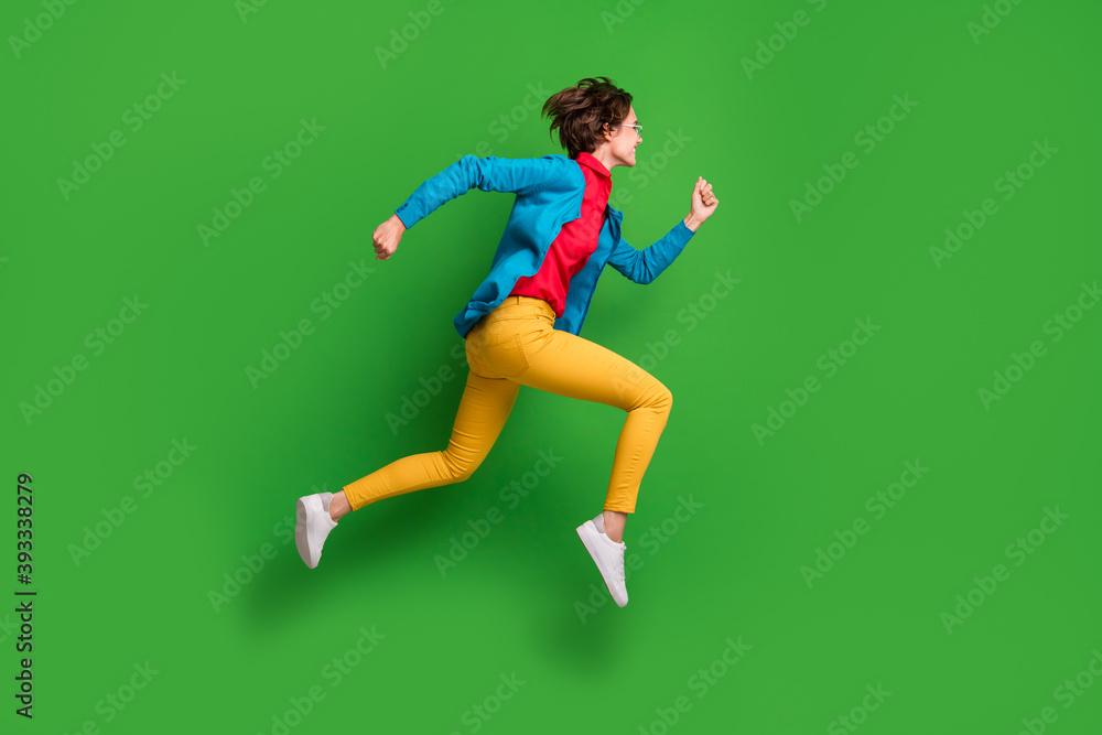 Full length body size side profile photo of jumping running girl in colorful clothes isolated on vibrant green color background Full length body size side profile photo of jumping running girl in colorful clothes isolated on vibrant green color background