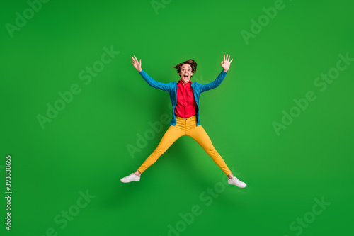 Full length body size photo of careless childish female student jumping like star isolated on bright green color background © deagreez
